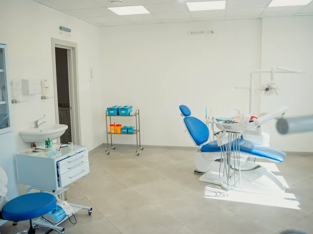 Behandlungszimmer der Praxis mit blauer Behandlungseinheit, Waschplatz und Tageslicht
